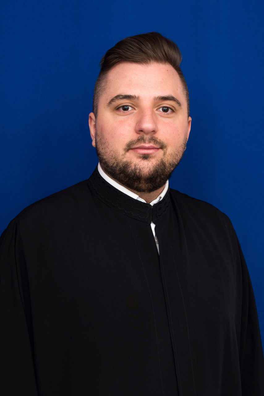 Florian Mihai Vois wearing a black coat against a blue background